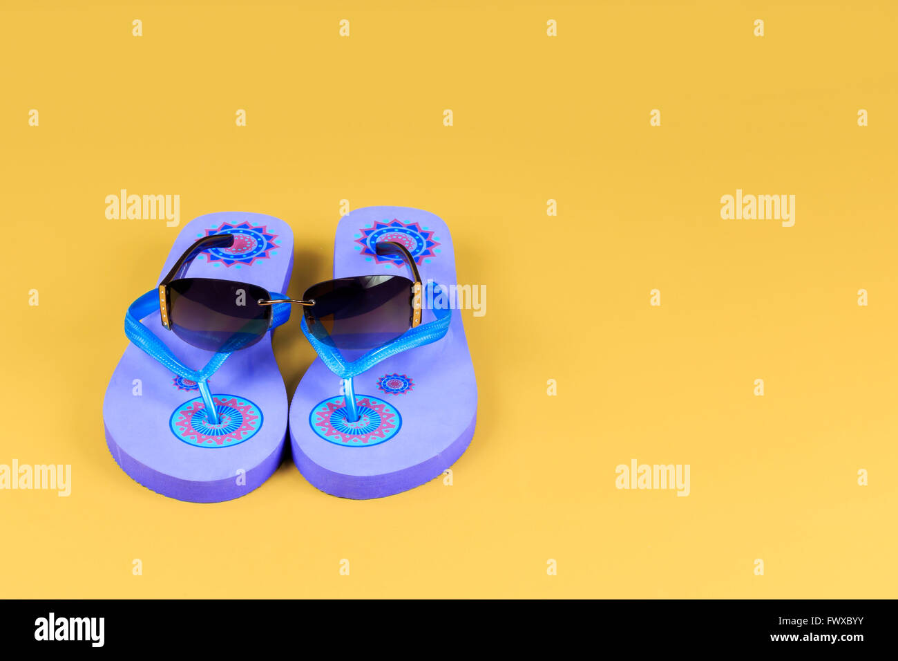 Paar blau Flip Flops und Sonnenbrillen auf gelbem Hintergrund Stockfoto