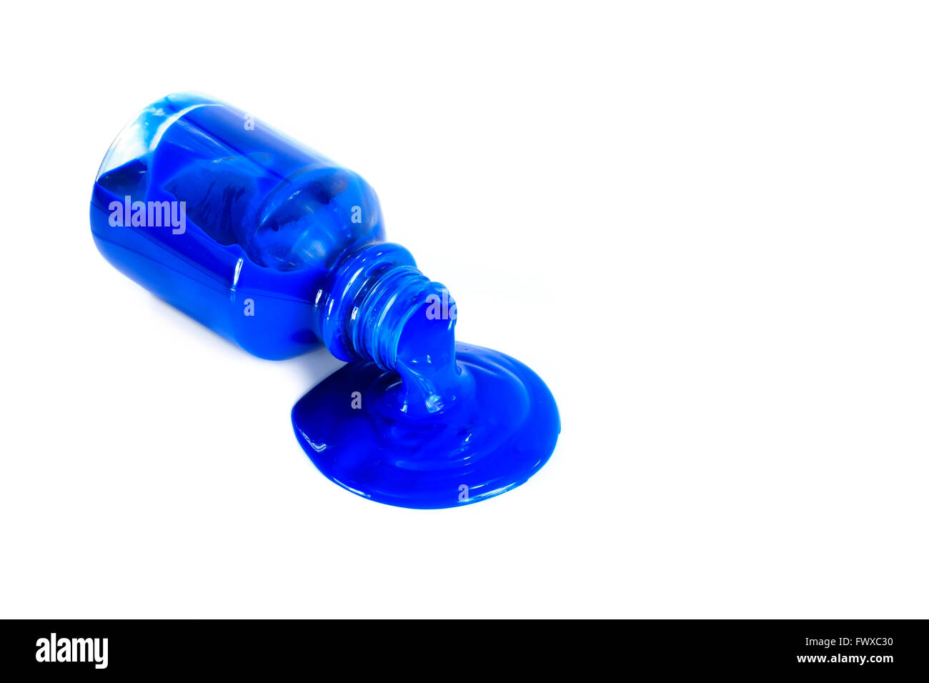 Blaue Farbe, die aus einer Flasche, isoliert auf weiss gießen Stockfoto