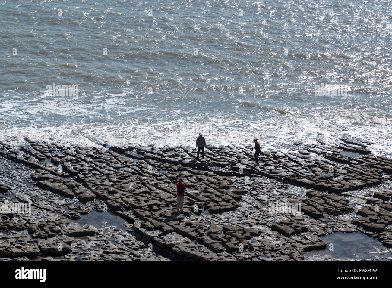 Eine Gruppe von Menschen stehen auf Felsen beobachten die Flut ausgehen. Stockfoto