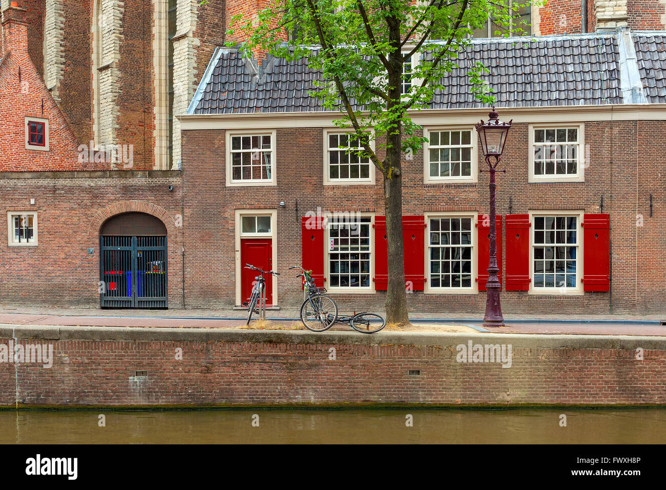 Fahrräder auf der schmalen Straße zwischen Kanal und Backstein-Haus in Amsterdam, Niederlande. Stockfoto