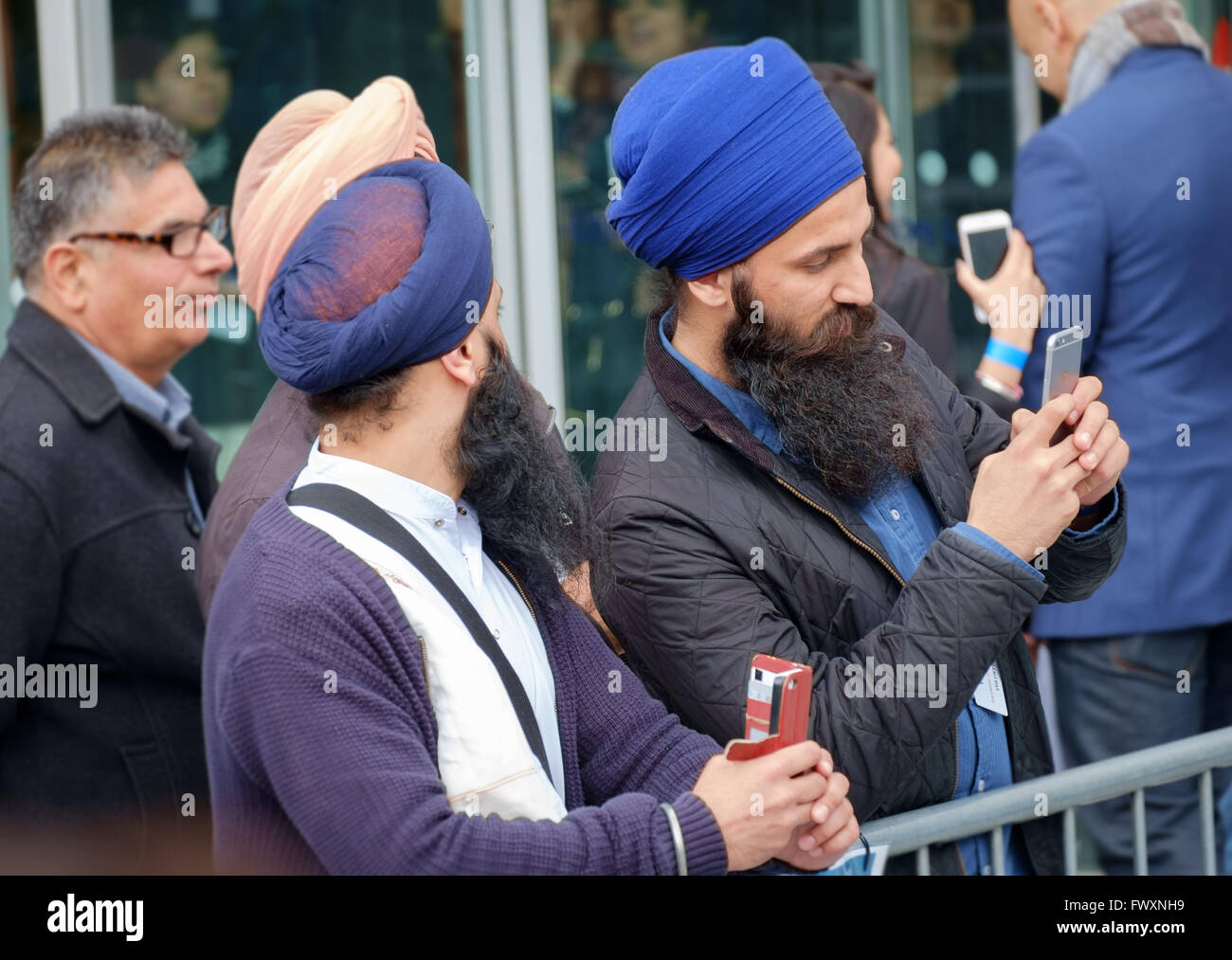 Sikh-Männer in traditioneller Kleidung nutzen Mobiltelefone, Film im Rahmen des Festivals der Vaisakhi statt im Rathaus, London, April 2016 Stockfoto