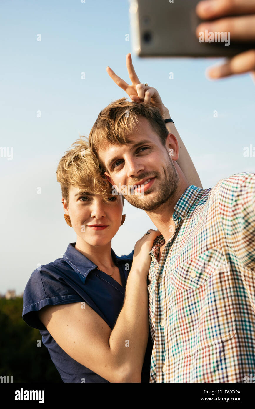 Deutschland, Berlin, junges Paar umarmt und unter Selfie mit Smartphone Stockfoto