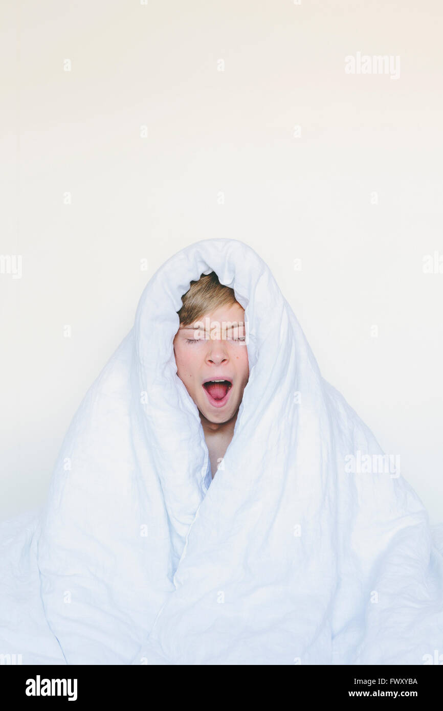 Finnland, Helsinki, Porträt von gähnenden junger Mann in weißen Decke eingewickelt Stockfoto