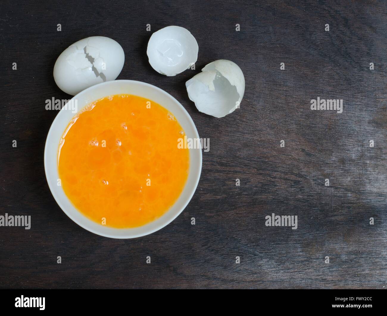 schlagen von Eiern in Schüssel auf Holz Hintergrund Stockfoto