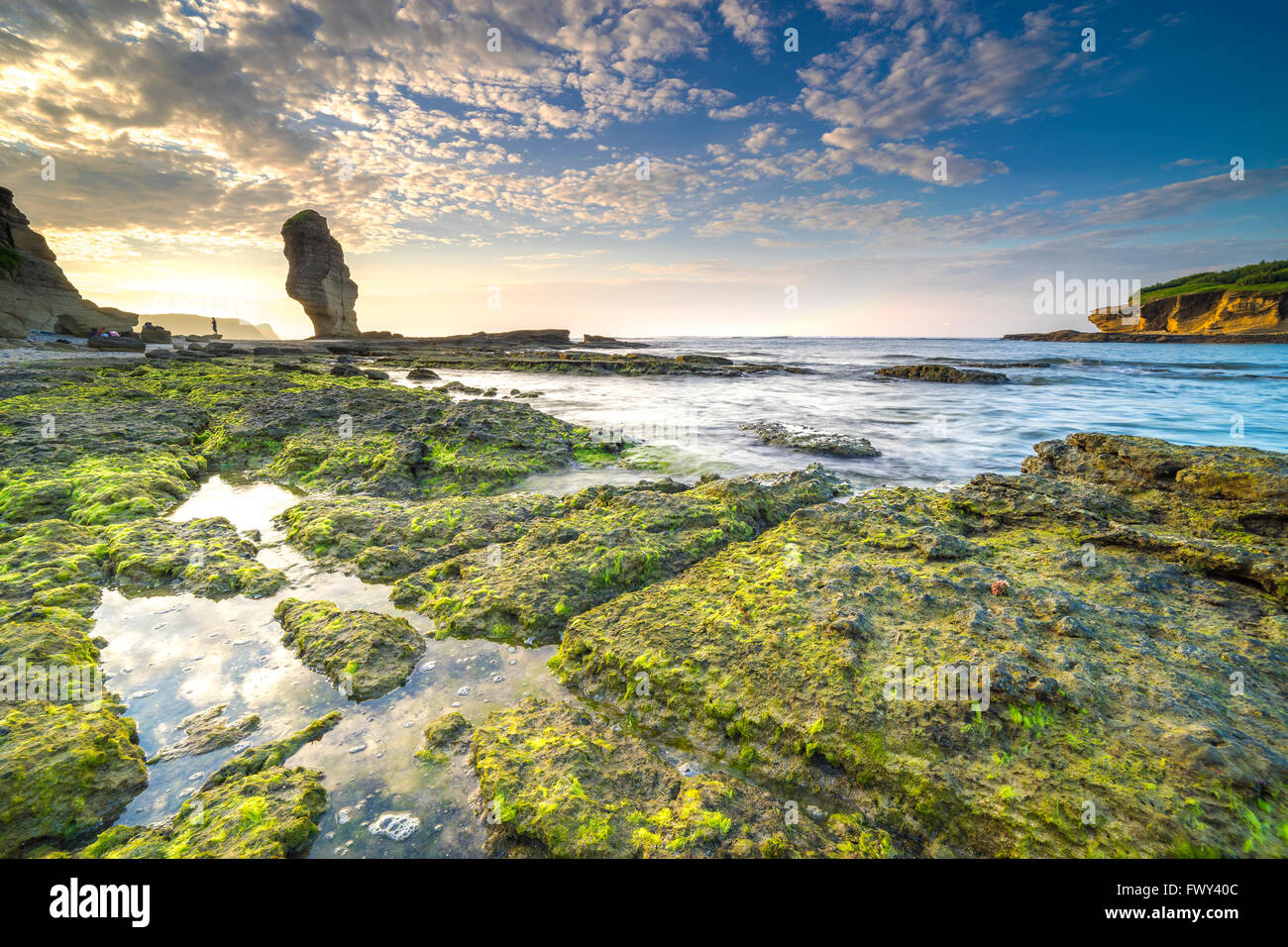 Rock grünes Moos mit Sonnenaufgang Hintergrund am Pantai Batu Payung (Umbrella Felsstrand) Lombok, Indonesien. Stockfoto