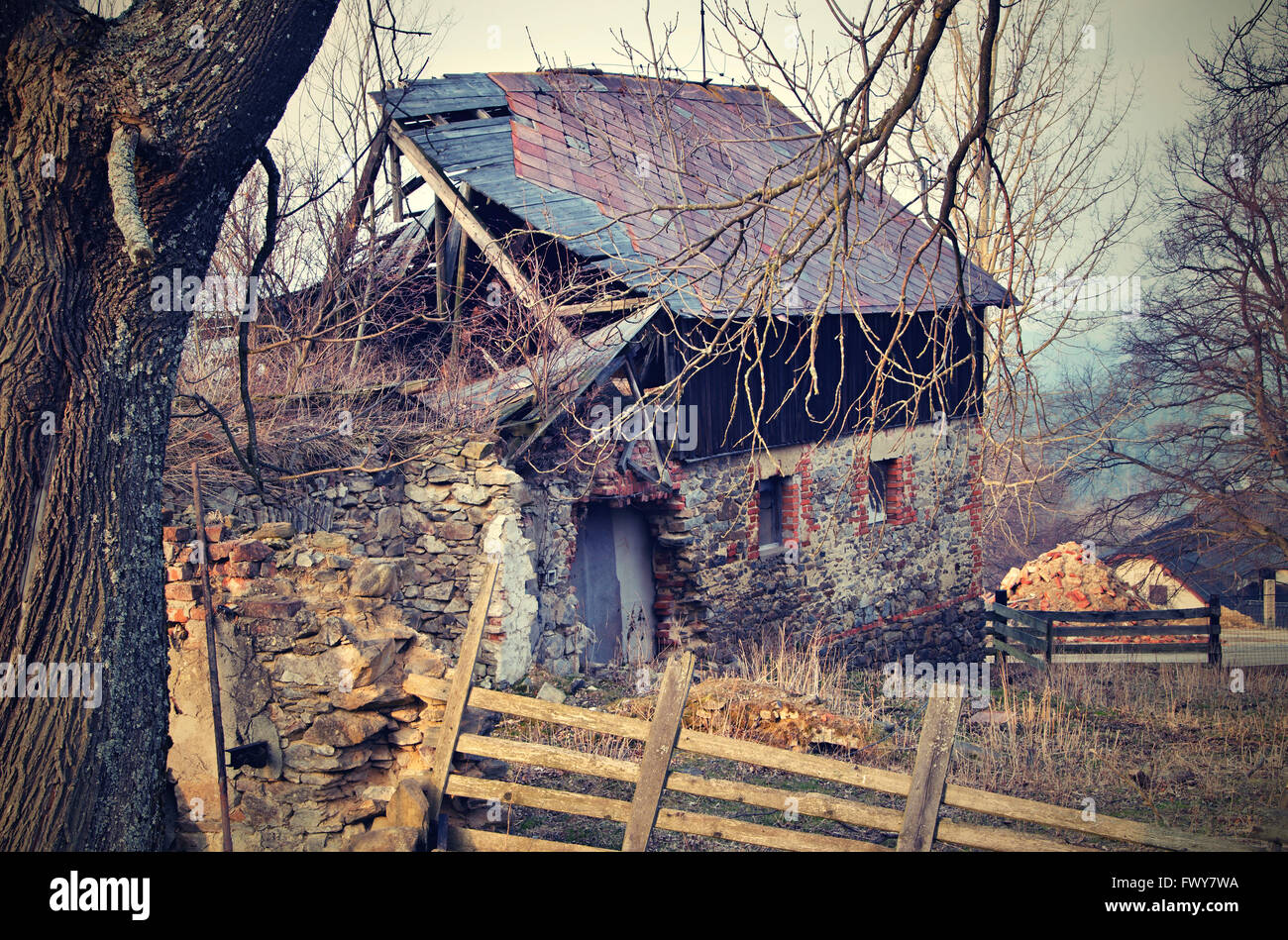 Verlassene unkultivierten Hütte hinter Baum und Zaun Stockfoto