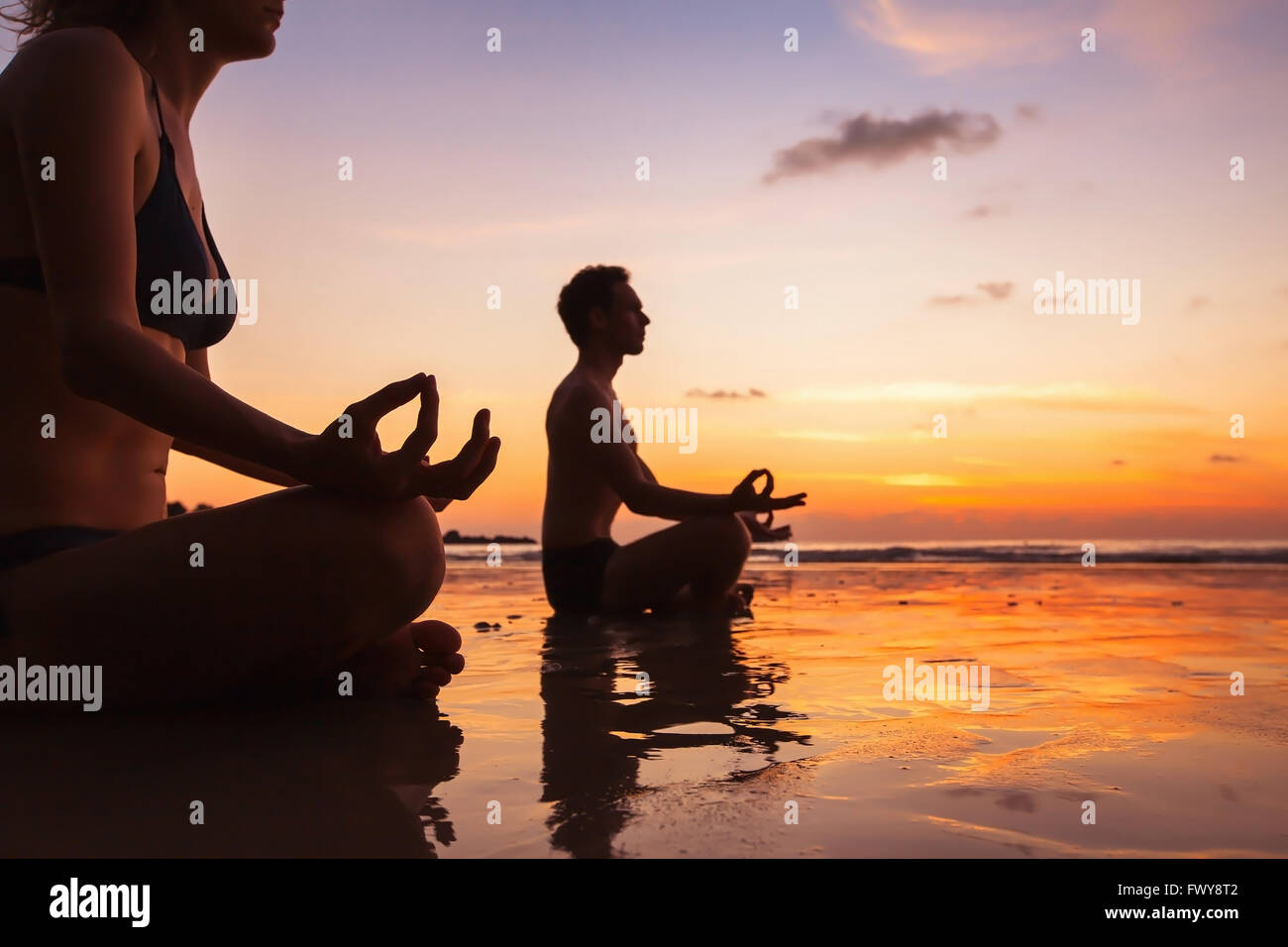 Gruppe von Menschen, die meditieren auf dem Strand, Yoga und Gesundheit Hintergrund Stockfoto