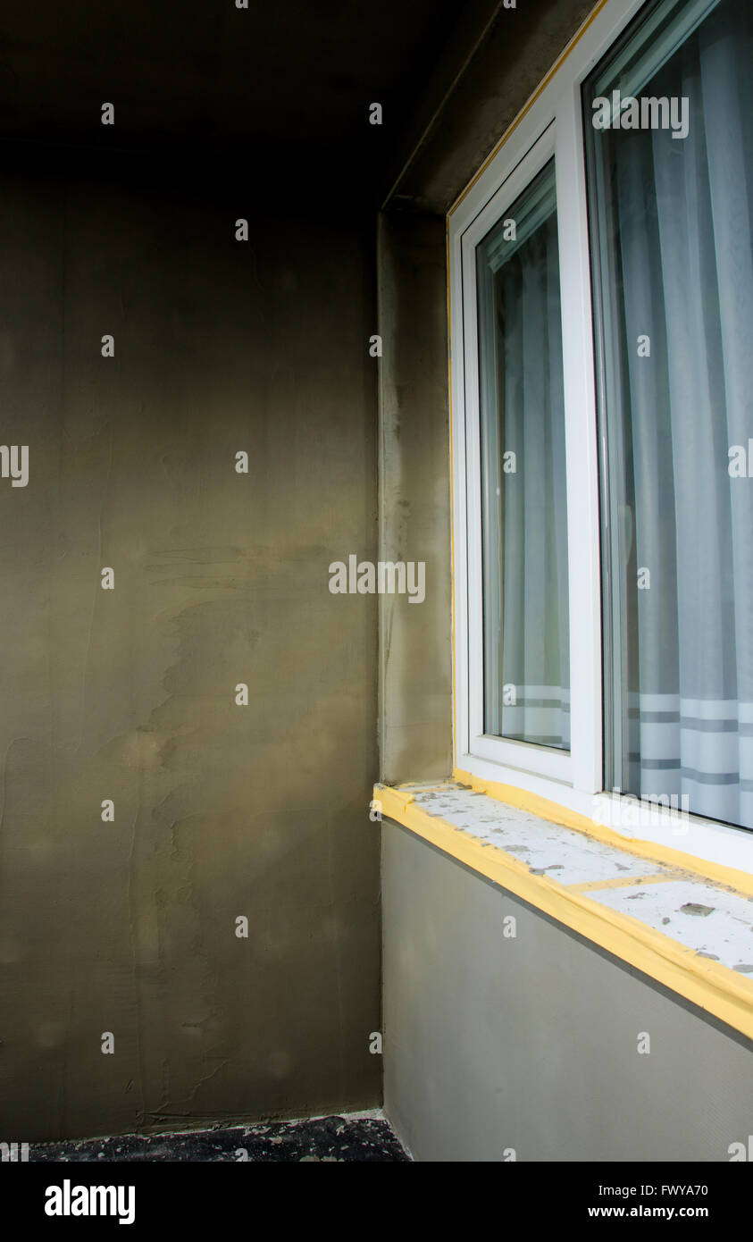 Halbfabrikate Reparatur Balkon, graue Putz und schmutzig weißes Fenster. Stockfoto