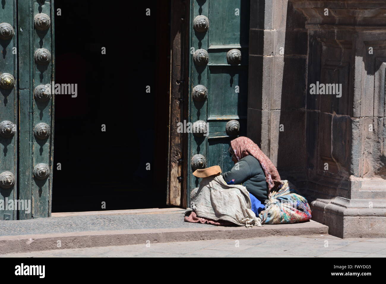 Eine alte Frau bittet vor den Toren von La Merced katholische Kirche in Cusco-Peru. Stockfoto