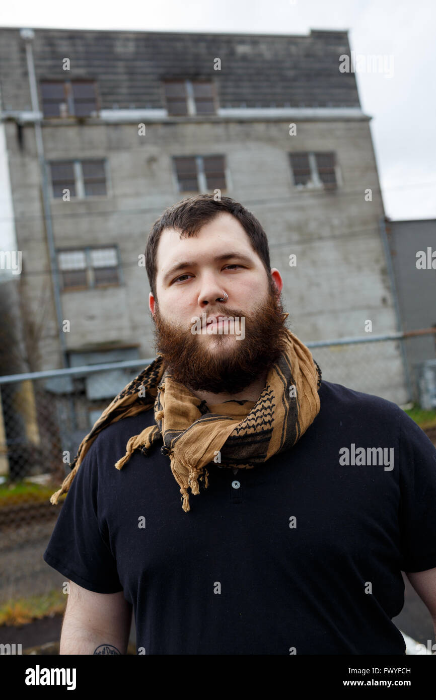 Junger Erwachsener Mann im Freien in einem städtischen Umfeld für Lifestyle Portrait eines bärtigen Hipster. Stockfoto