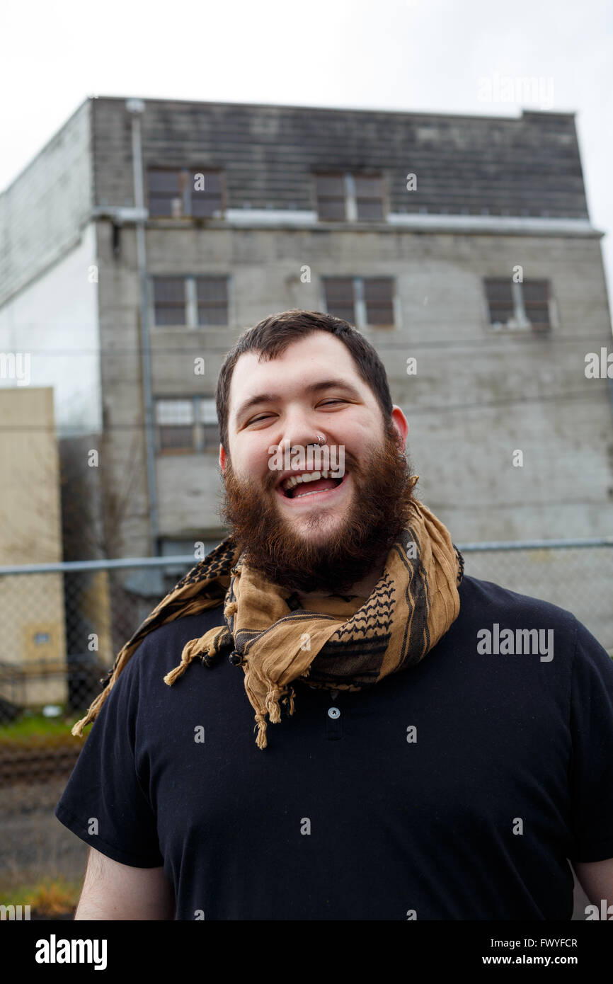 Junger Erwachsener Mann im Freien in einem städtischen Umfeld für Lifestyle Portrait eines bärtigen Hipster. Stockfoto