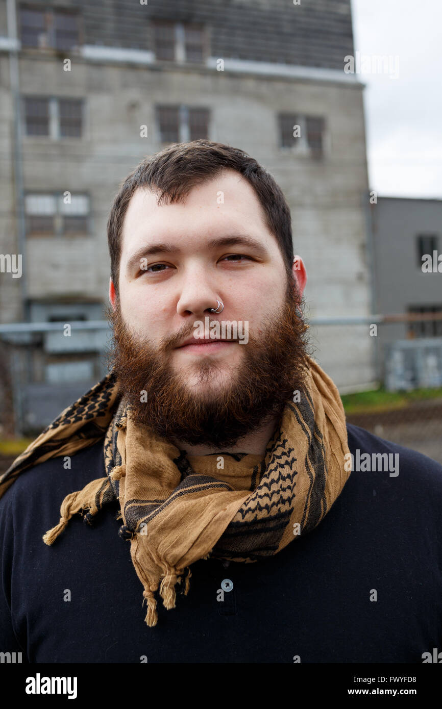 Junger Erwachsener Mann im Freien in einem städtischen Umfeld für Lifestyle Portrait eines bärtigen Hipster. Stockfoto