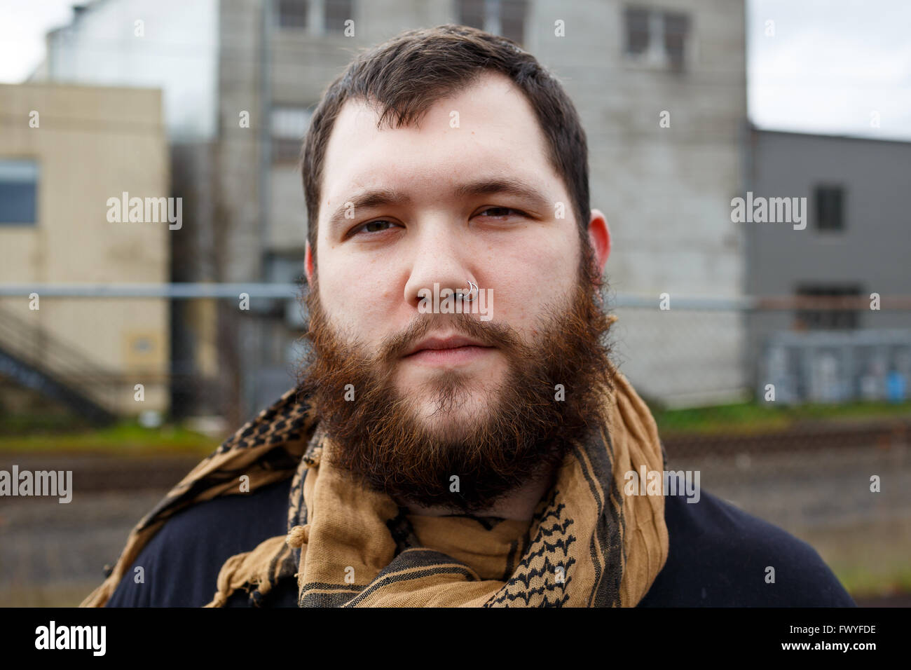 Junger Erwachsener Mann im Freien in einem städtischen Umfeld für Lifestyle Portrait eines bärtigen Hipster. Stockfoto