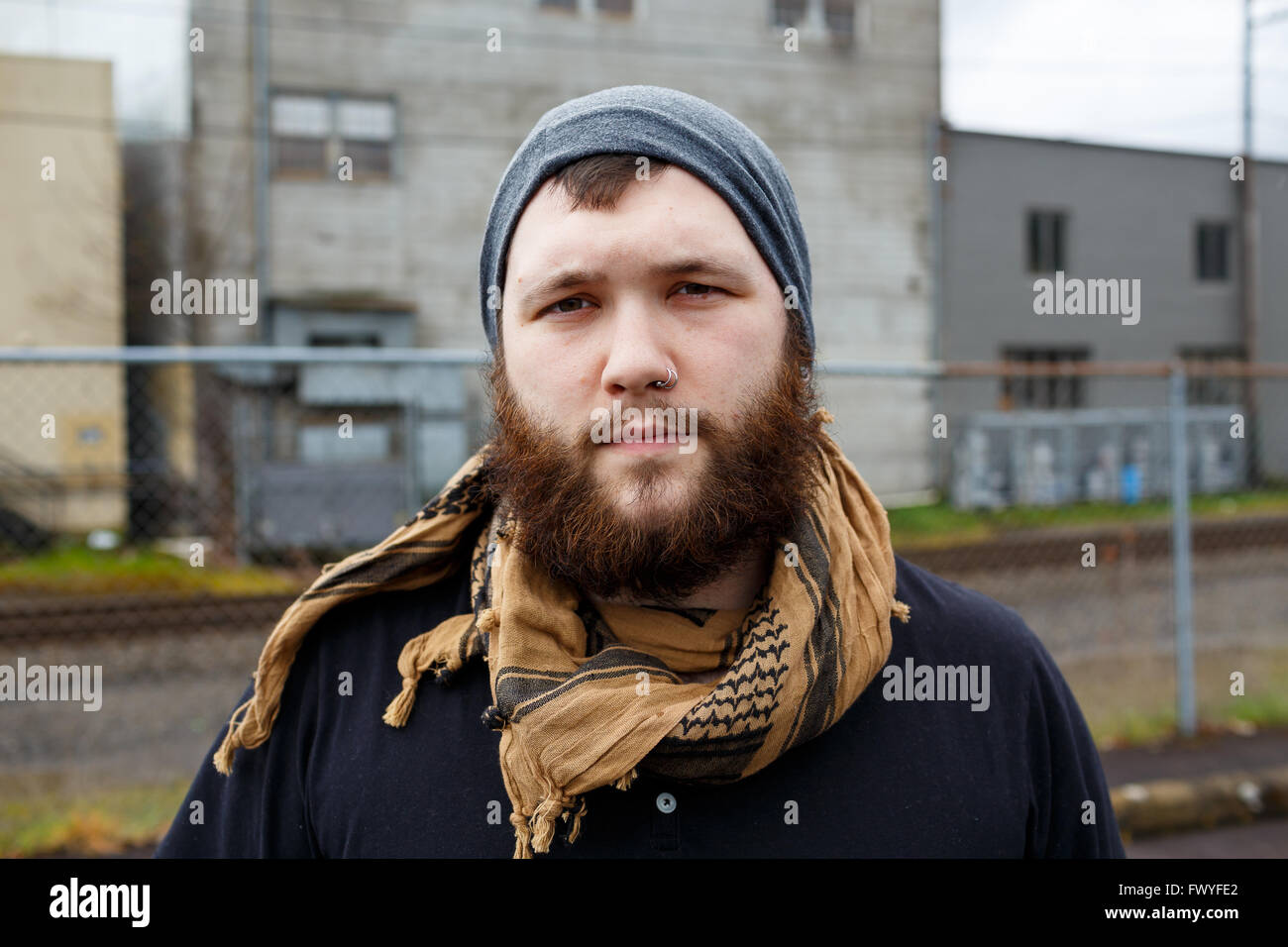 Junger Erwachsener Mann im Freien in einem städtischen Umfeld für Lifestyle Portrait eines bärtigen Hipster. Stockfoto