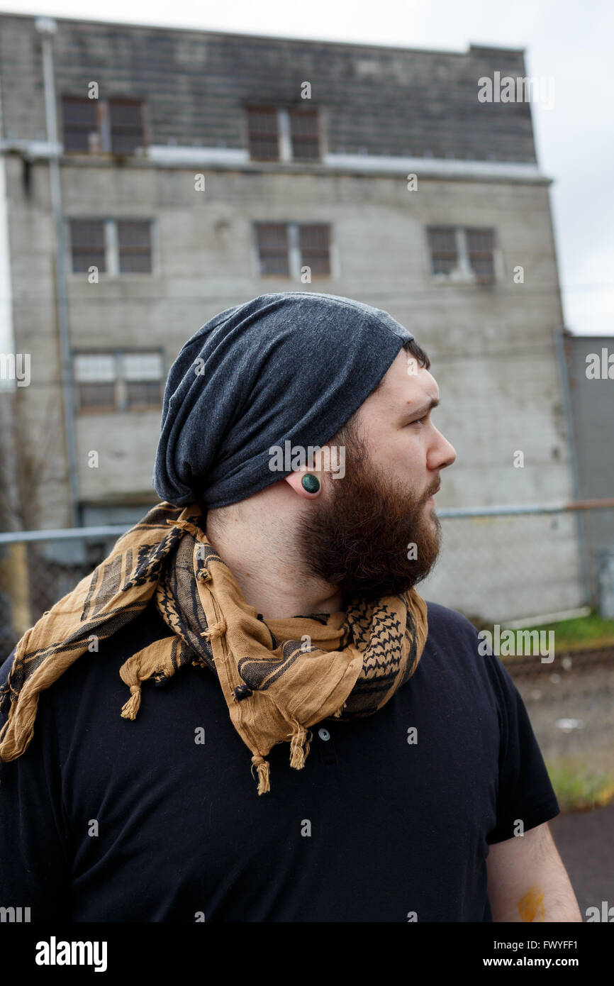 Junger Erwachsener Mann im Freien in einem städtischen Umfeld für Lifestyle Portrait eines bärtigen Hipster. Stockfoto