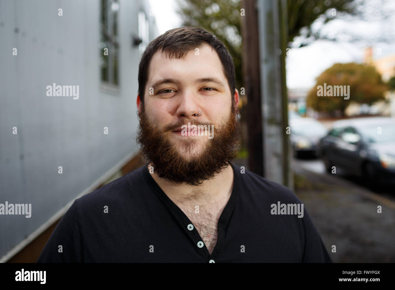 Junger Erwachsener Mann im Freien in einem städtischen Umfeld für Lifestyle Portrait eines bärtigen Hipster. Stockfoto