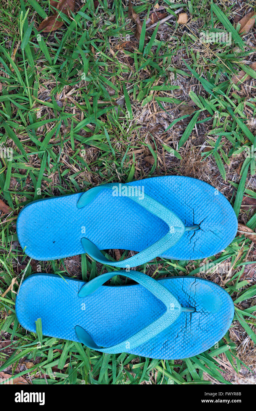 Aus blauen Riemen oder Flip-Flops gegen Rasengras abgenutzt getragen. Stockfoto