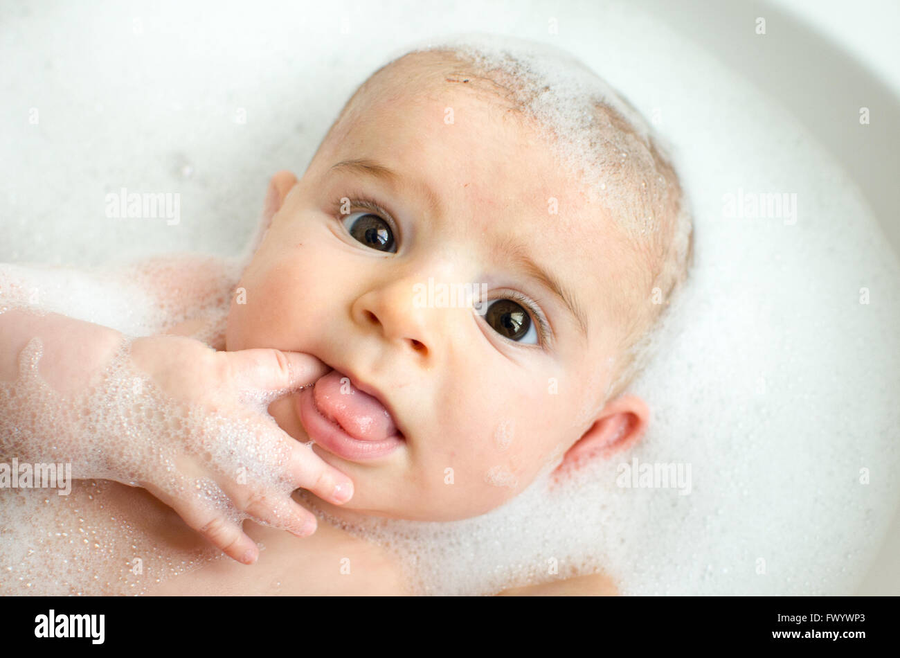 Neugeborenen Schaumbad weißer Schaum Finger Essen waschen Baby Pflege große Augen braun Stockfoto