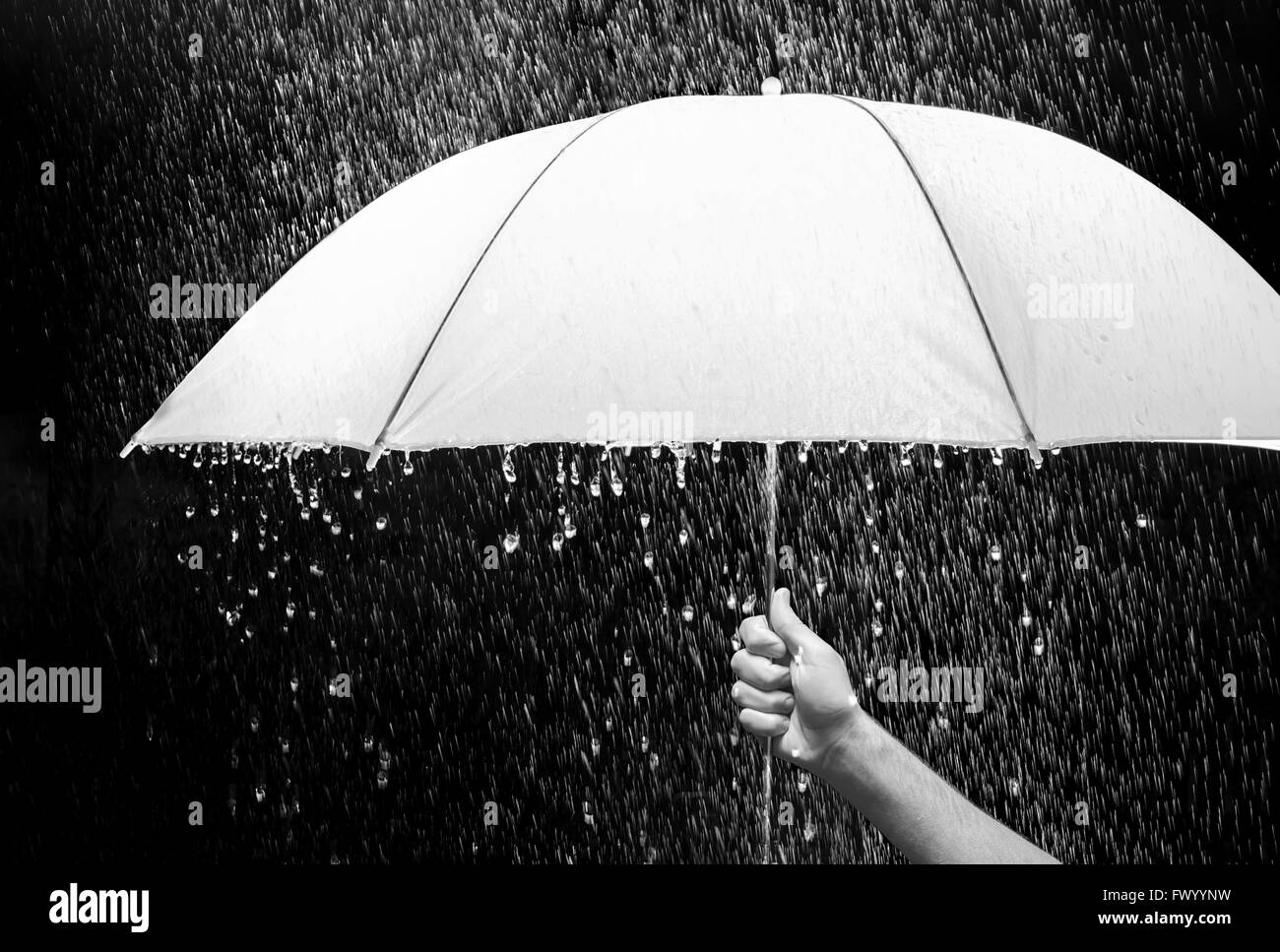 Hand, die einen Schirm im Regen, schwarzer Hintergrund - Geschäft und Modekonzept. Stockfoto