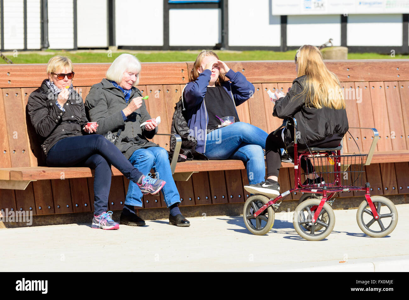 Simrishamn, Schweden - 1. April 2016: Vier Personen verschiedenen Alters zusammen sitzen essen Eis in der Sonne. Man sitzen Stockfoto