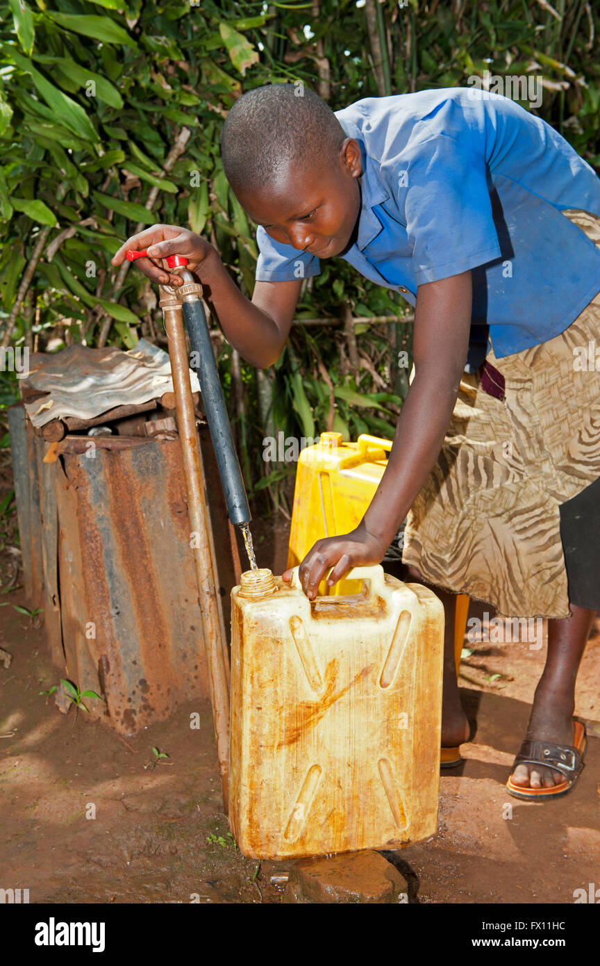 Ruandische Mädchen Füllung Behälter mit frischem Wasser aus einem Hahn. Stockfoto