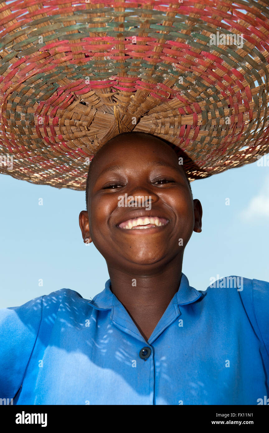 Lächelndes ruandischen Mädchen mit Korb auf dem Kopf. Stockfoto