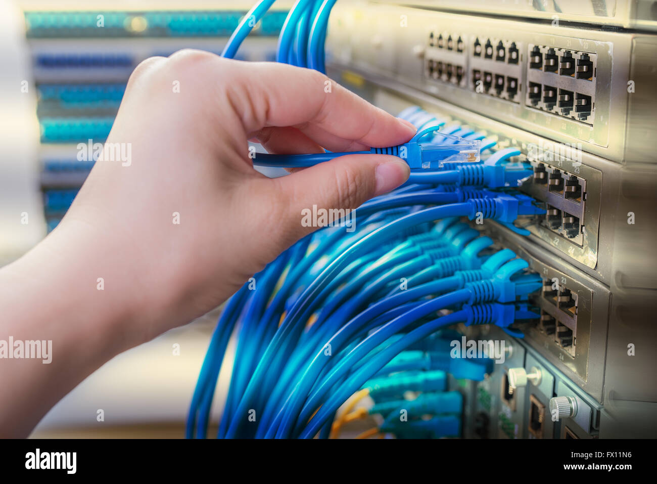 Hand mit Netzwerkkabel verbunden zu Servern in einem Rechenzentrum Stockfoto