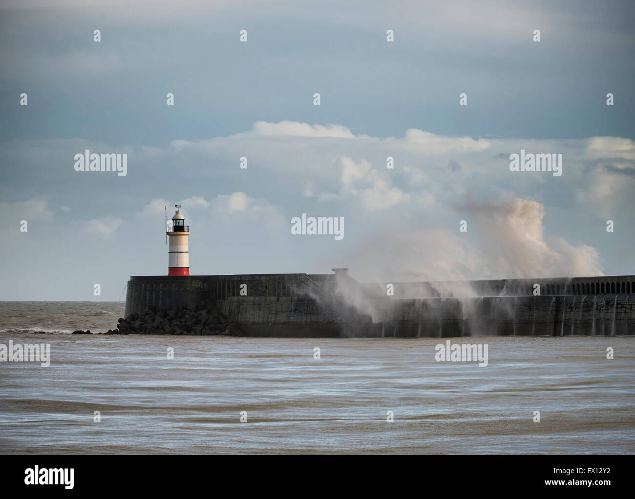 Großes Meereswellen, die über Leuchtturm im Sturm mit schönen Abendlicht Stockfoto