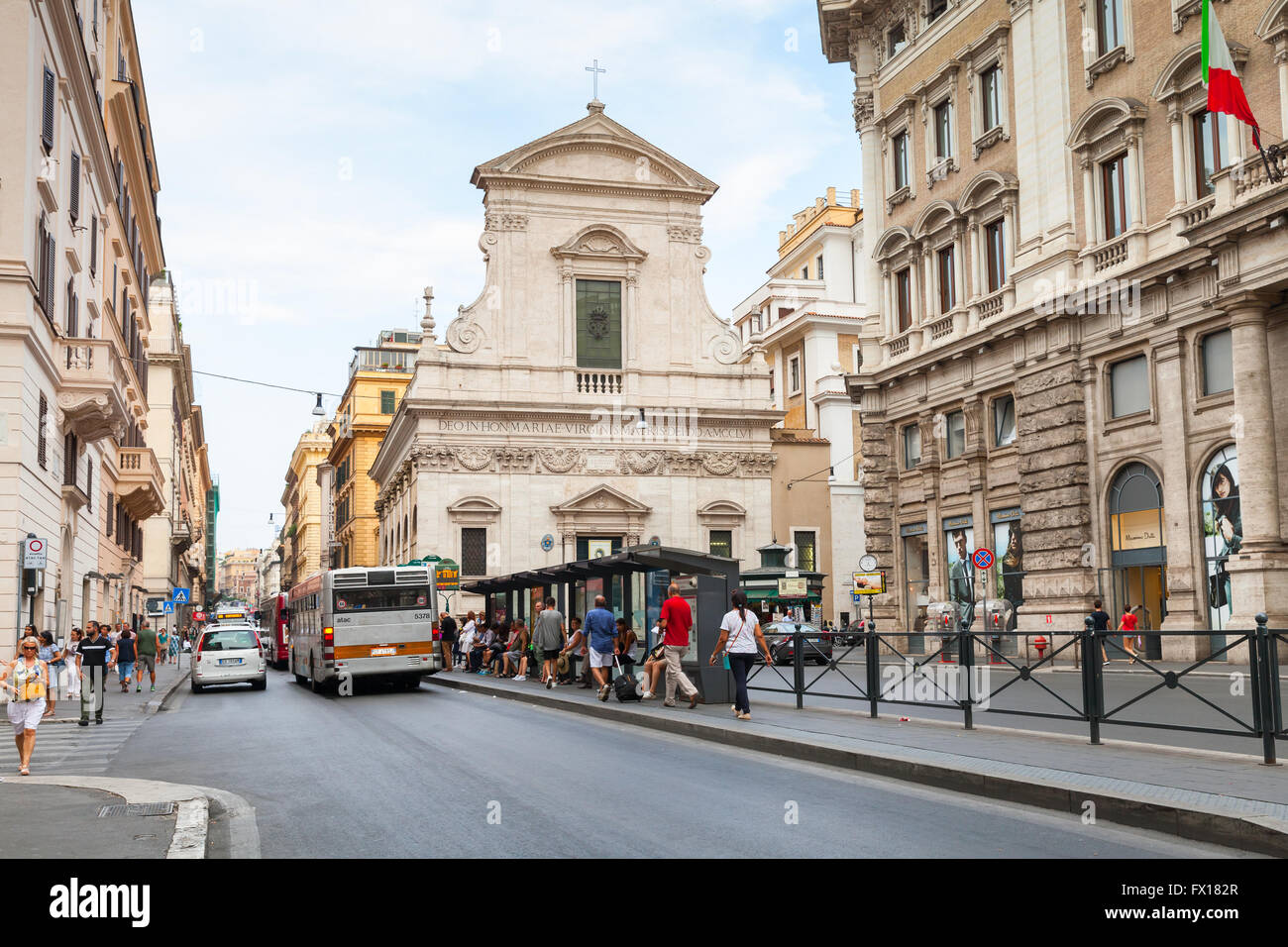 Rom - 7. August 2015: Straßenansicht von Largo Chigi mit gewöhnlichen Menschen auf eine Bushaltestelle und Chiesa di Santa Maria in Via bas Stockfoto