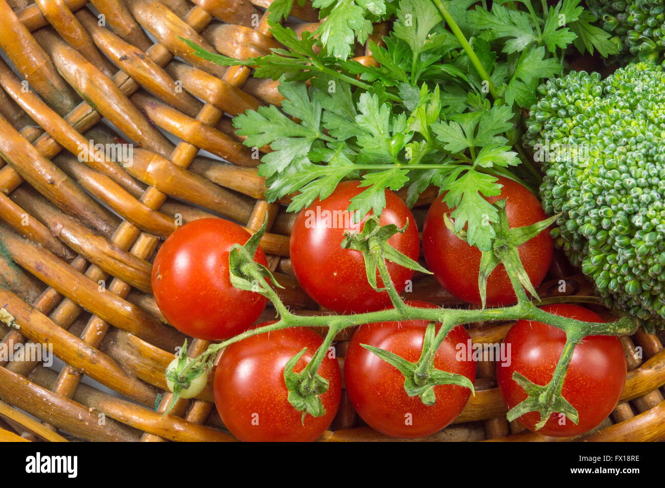 Cherry-Tomaten mit Petersilie und Broccoli auf einer Holzplatte Stockfoto