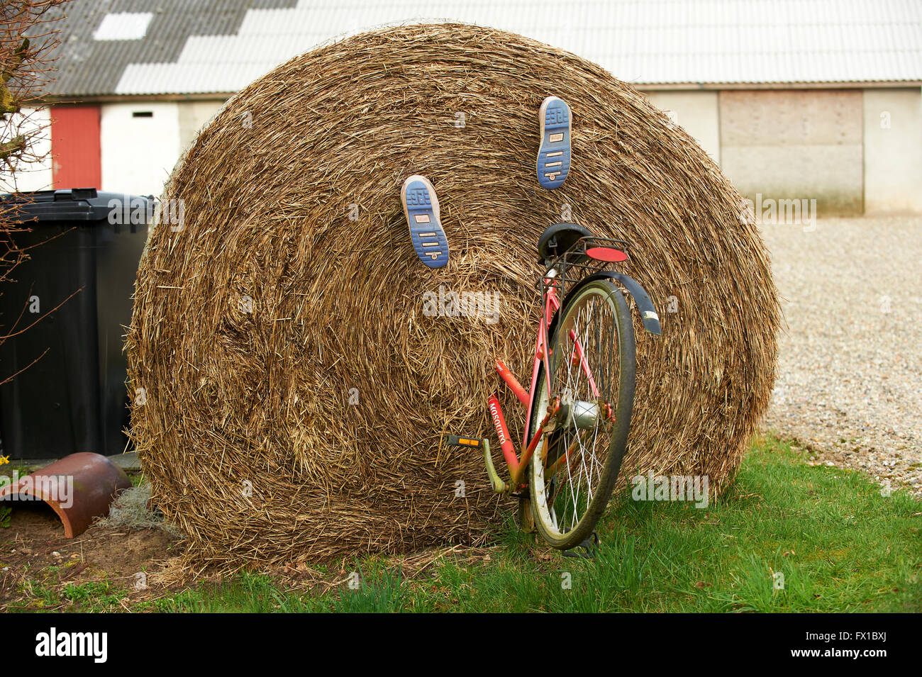 Großballen Stroh mit Fahrrad und Gummistiefel montiert, die aussehen, als ob die Person Reiten sie in den Ballen verschwunden ist Stockfoto