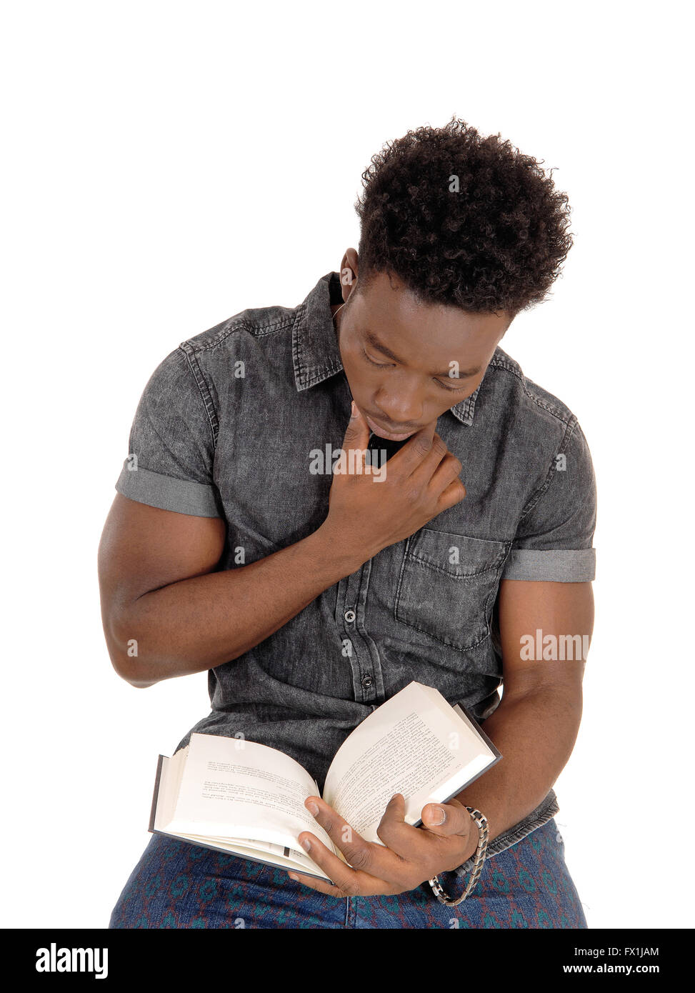 Ein junger afrikanischer Amerikaner Mann auf einem Stuhl sitzen und lesen ein Buch für den weißen Hintergrund isoliert. Stockfoto