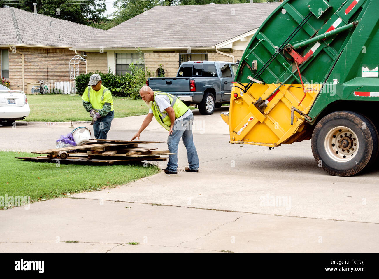 Zwei Männer laden Sie Müll in einem Müllwagen auf großen Trash-Tag in Oklahoma City, Oklahoma, USA. Stockfoto