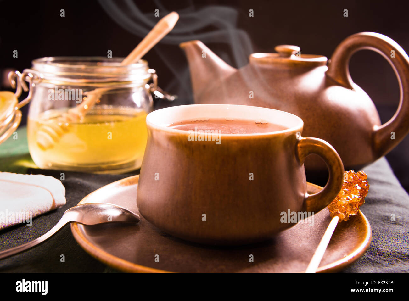 Eine Tasse heißen Tee auf einem Tisch mit Teekanne und Honig im Hintergrund Stockfoto