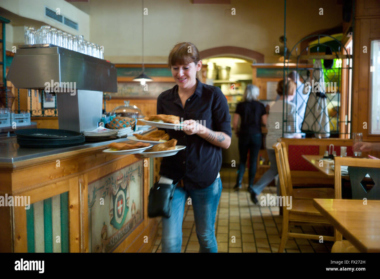Eine Kellnerin in dem Beisl Cafe Vianna Wiener Schnitzel serviert Stockfoto