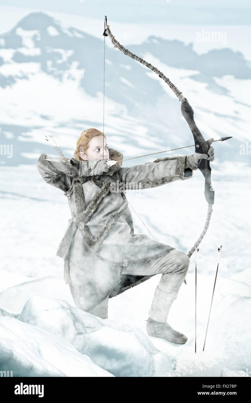 Wildes Mädchen Bogenschütze im Schnee mit Bogen Stockfoto