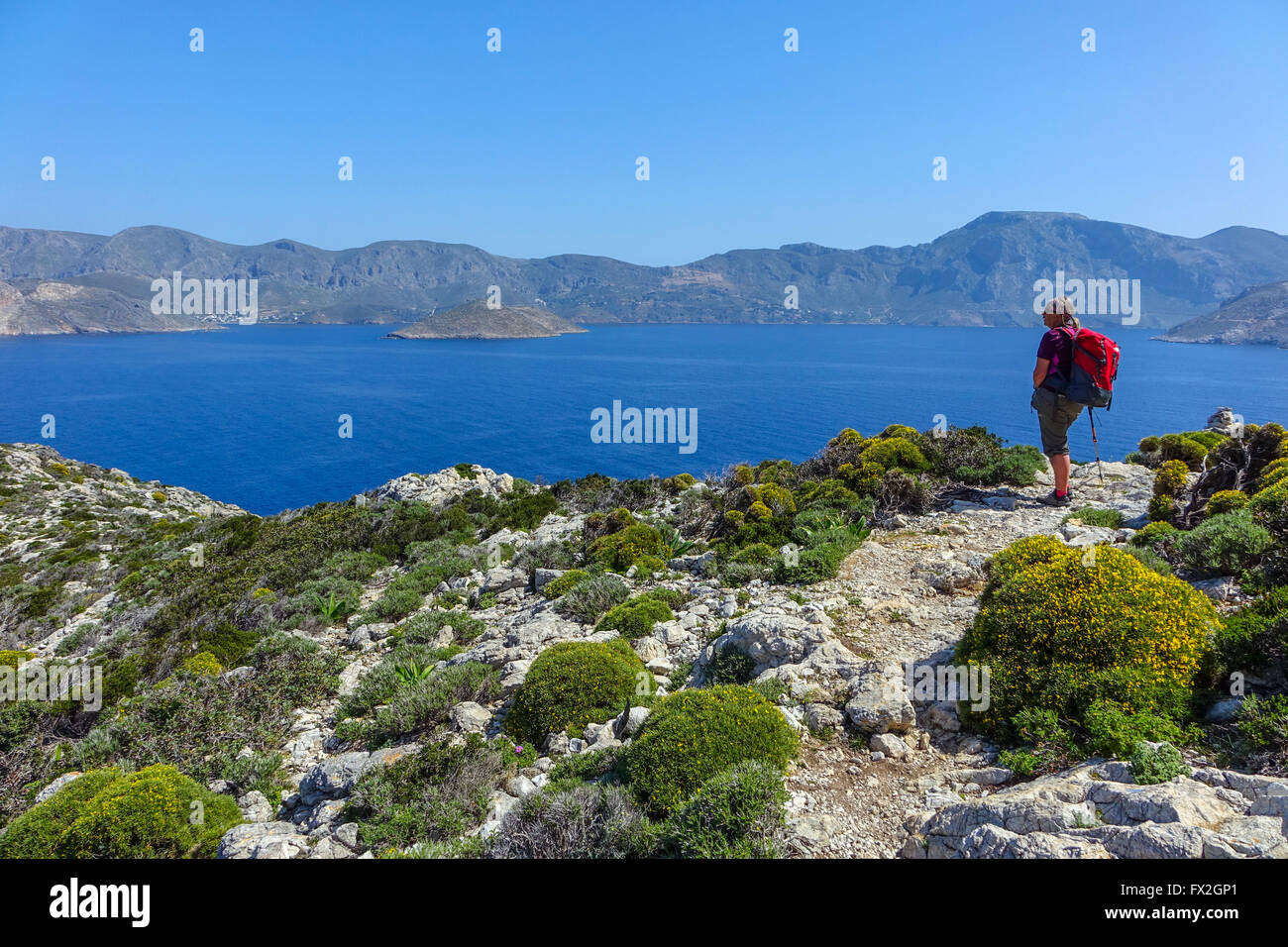 Weibliche Walker mit roten Rucksack, blaues Meer und Berge in Emborios Bay Kalymnos, Griechenland Stockfoto