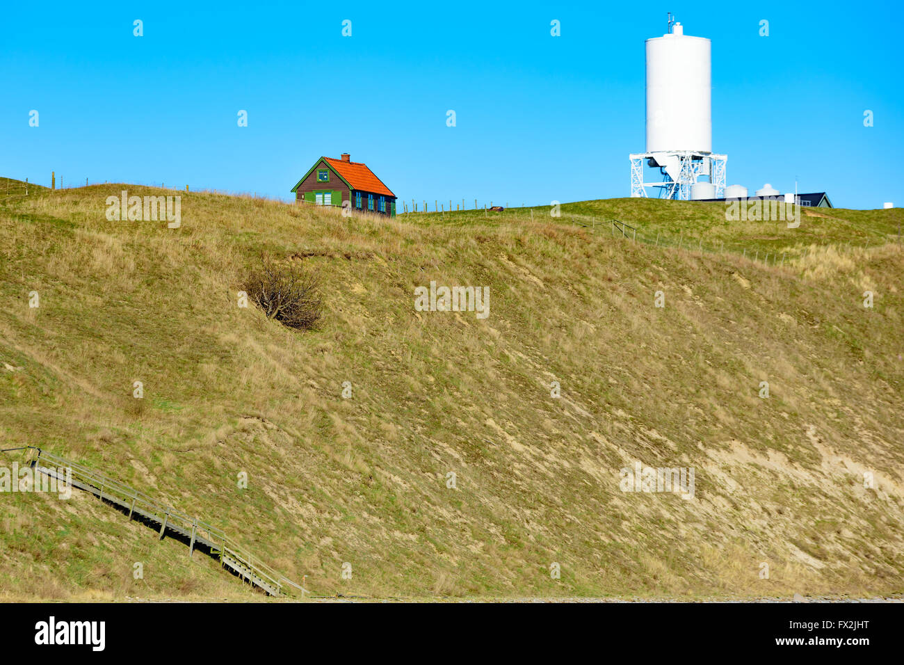 Kaseberga, Schweden - 1. April 2016: Schönes kleines Holzhaus befindet sich auf dem Hügel von einem sandigen Hügel. Bauernhof Silo im Hintergrund ein Stockfoto