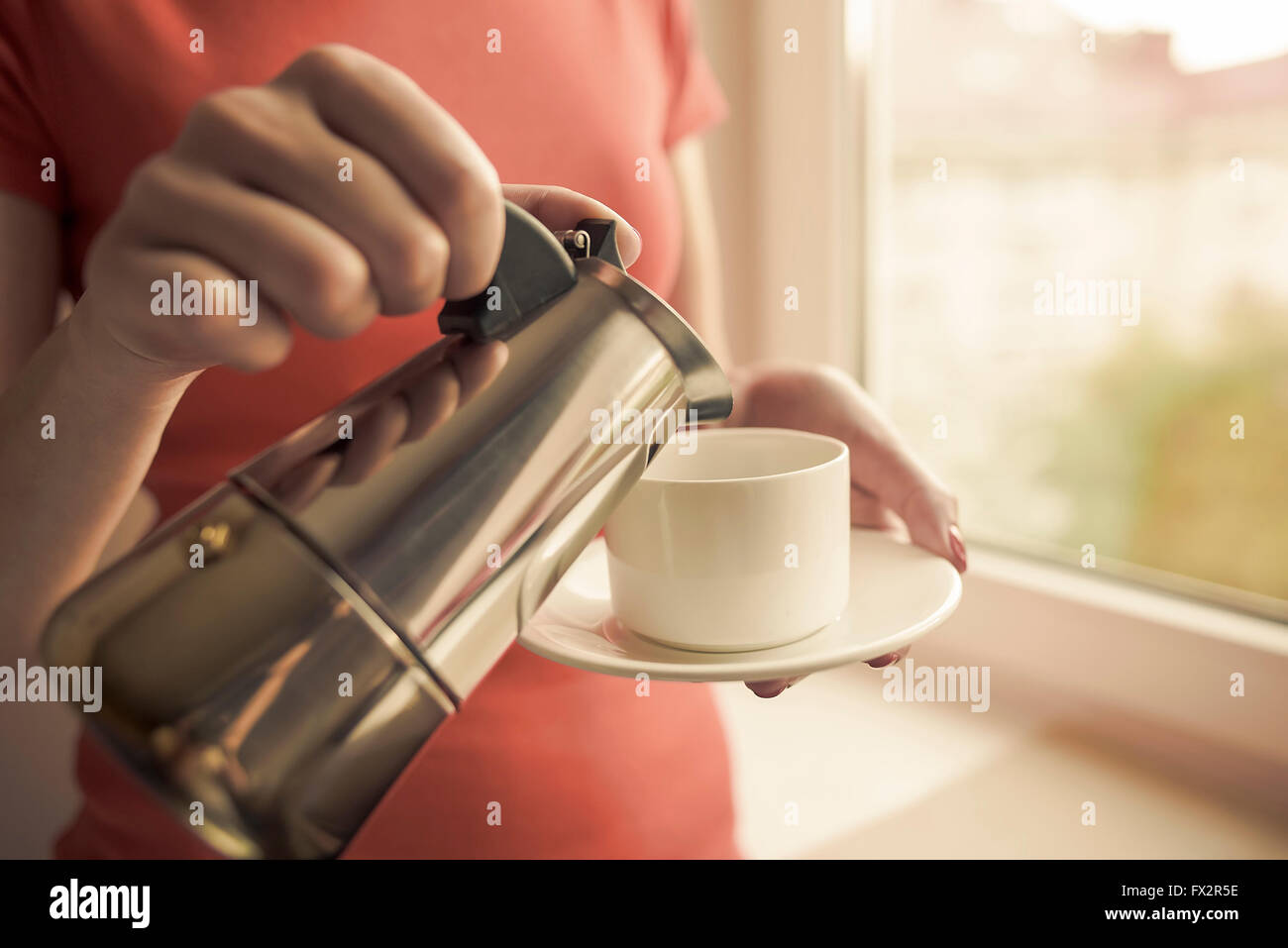 Weibliche Hand gießt Kaffee aus einer Kaffeemaschine ausgestattet. Kaffee im Fokus. Stockfoto