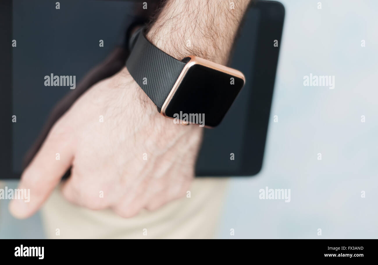 Männliche Hand mit zwei modernen digitalen Geräten immer mit Internet und social Media - trendige smart Watch und Tablet-pc verbunden sein. Stockfoto