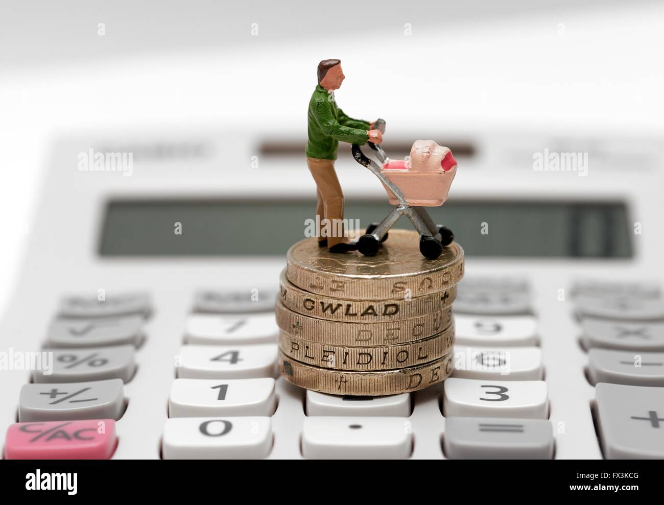 Einem einzigen männlichen Miniatur Figur Elternteil mit einem Kinderwagen stehen auf Pfund-Münzen und einen Taschenrechner Stockfoto