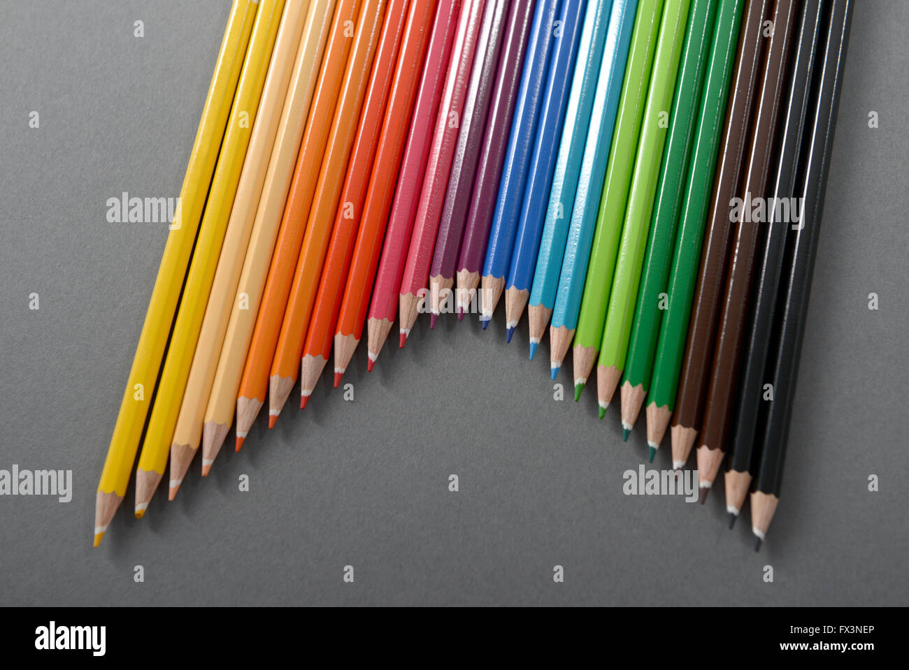 Buntstifte, angeordnet in einem V-Muster setzen vor einem grauen Hintergrund. Stockfoto