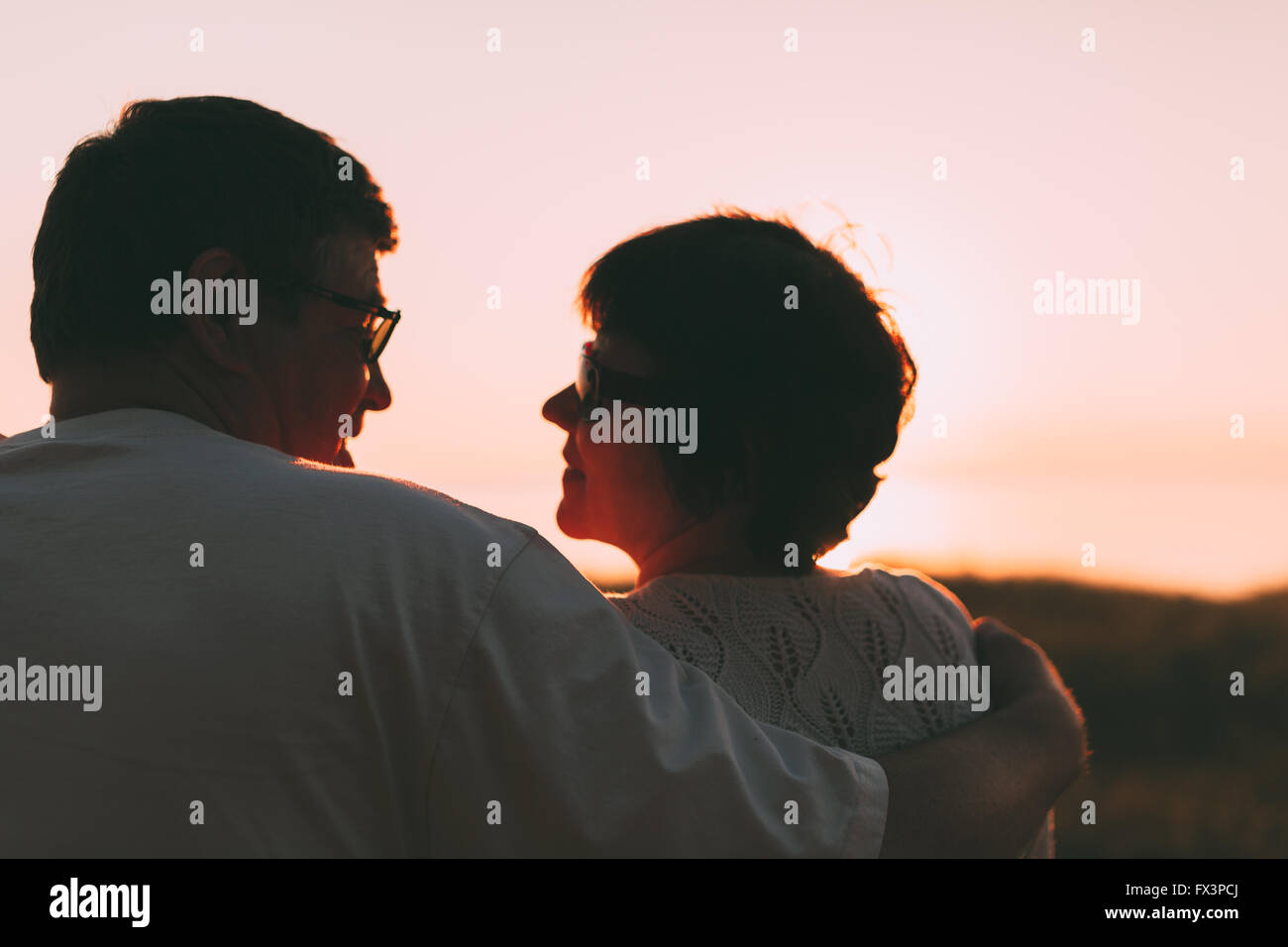 Erwachsenes paar umarmt bei Sonnenuntergang und Meer. Stockfoto