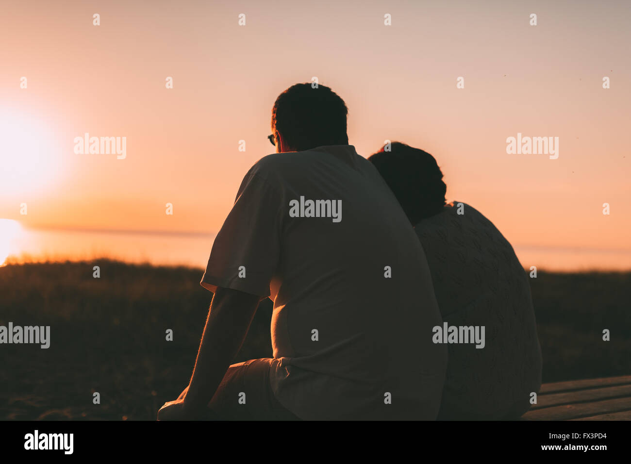 Seitenansicht ein Ehepaar eine Silhouette, die auf einer Bank sitzen. Stockfoto