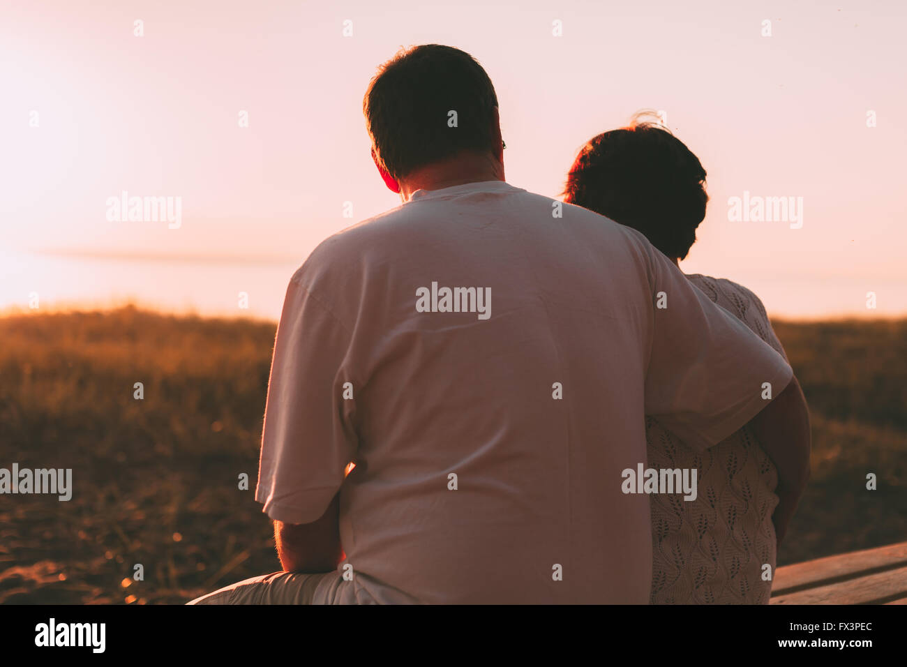 Erwachsenes paar umarmt bei Sonnenuntergang und Meer. Stockfoto