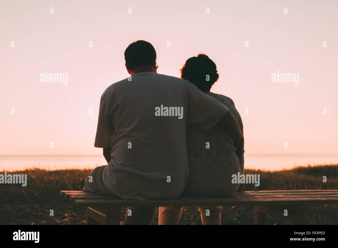 Erwachsenes paar umarmt bei Sonnenuntergang und Meer. Stockfoto