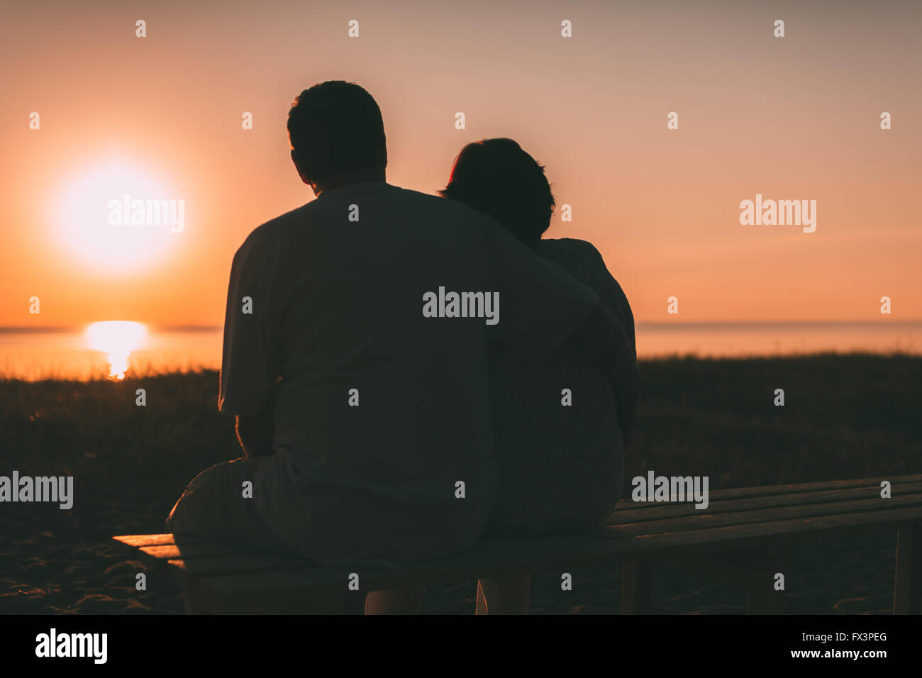 Erwachsenes paar umarmt bei Sonnenuntergang und Meer. Stockfoto