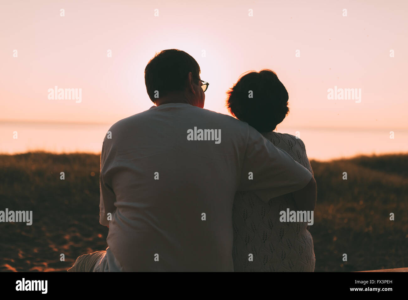 Erwachsenes paar umarmt bei Sonnenuntergang und Meer. Stockfoto