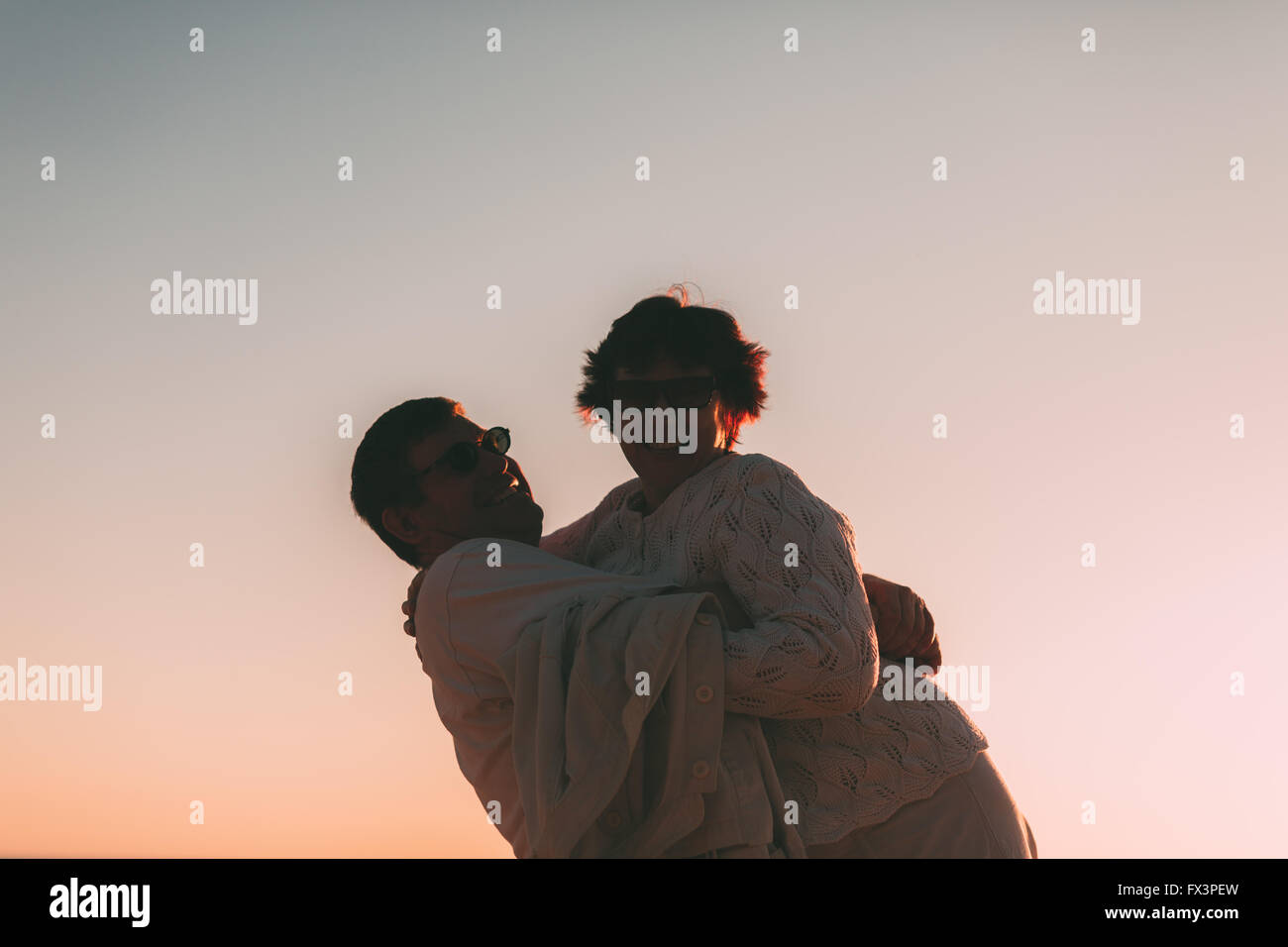 Erwachsenes paar umarmt bei Sonnenuntergang und Meer. Stockfoto