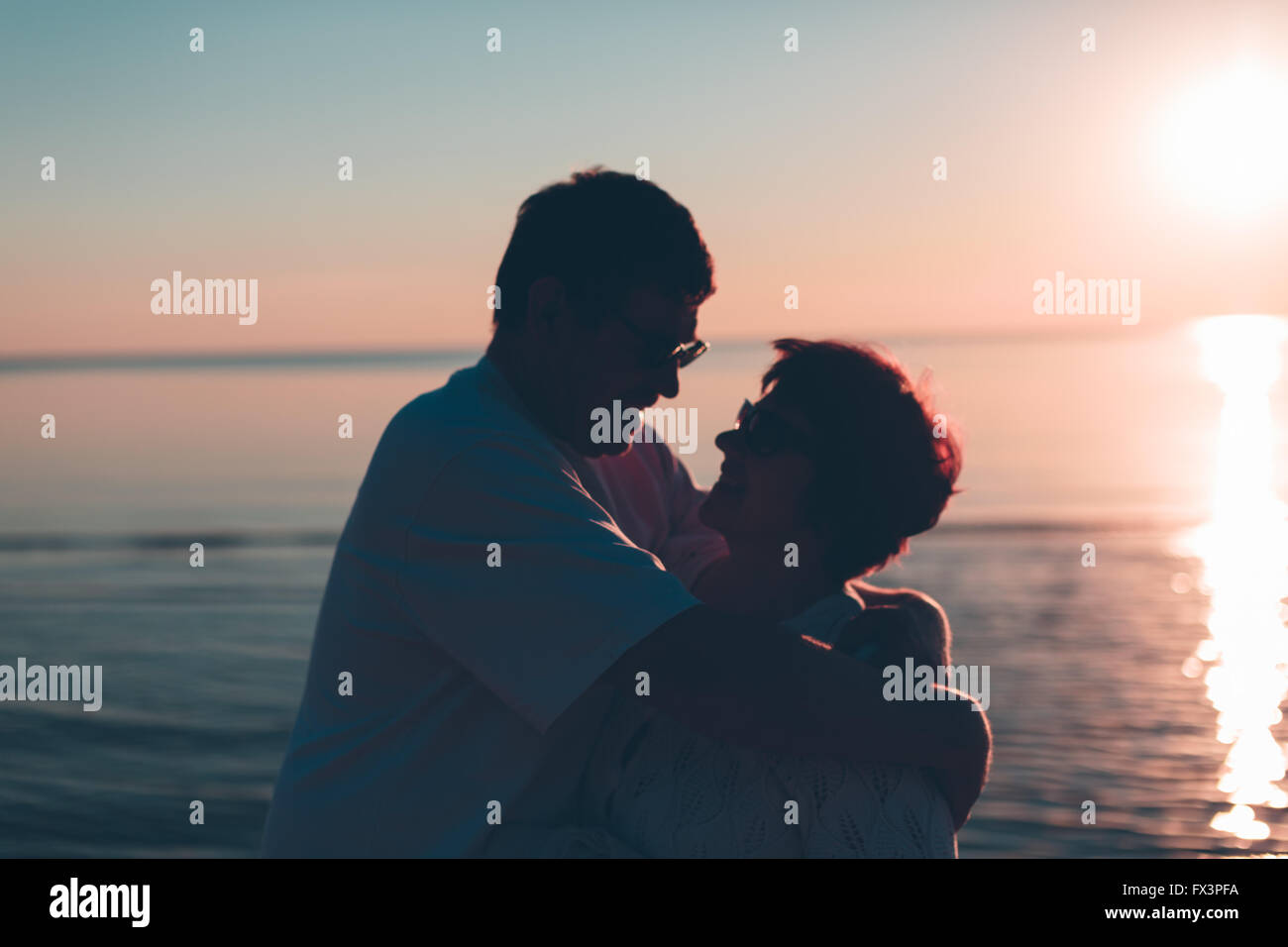 Erwachsenes paar umarmt bei Sonnenuntergang und Meer. Stockfoto
